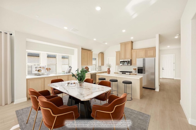 dining space with vaulted ceiling and light hardwood / wood-style flooring