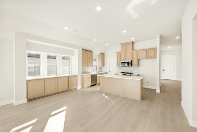 kitchen with light wood-type flooring, appliances with stainless steel finishes, a center island, and light brown cabinetry