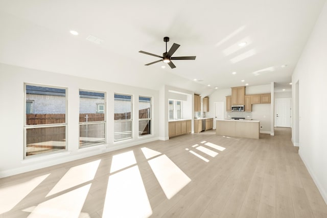 unfurnished living room featuring ceiling fan, light wood-type flooring, and vaulted ceiling