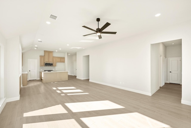 unfurnished living room with light wood-type flooring, vaulted ceiling, and ceiling fan