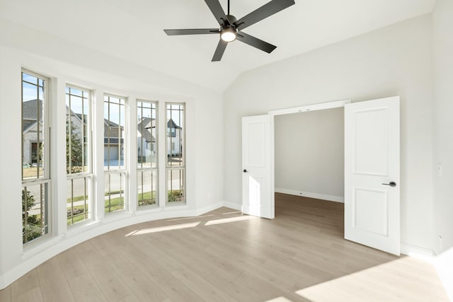 empty room featuring a wealth of natural light, light hardwood / wood-style flooring, ceiling fan, and vaulted ceiling