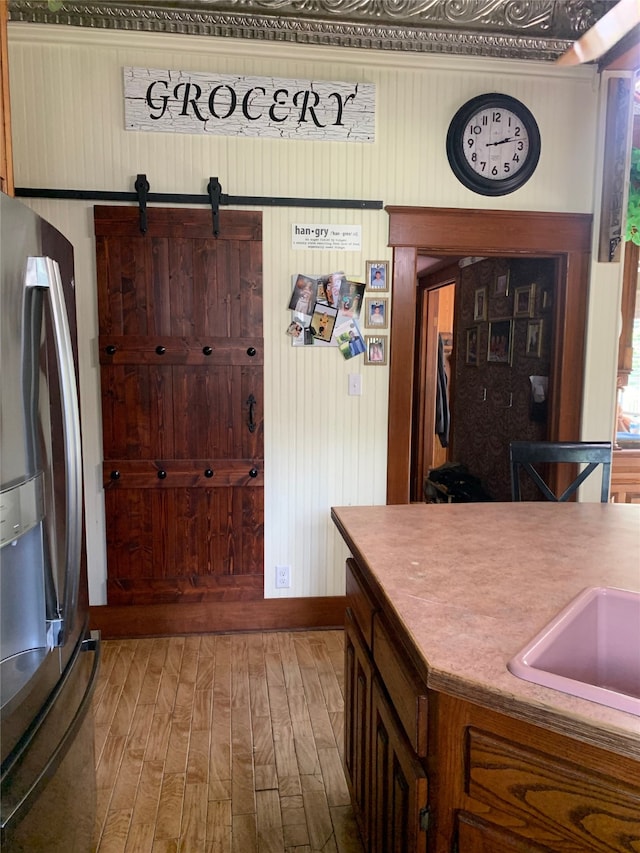 kitchen featuring wood-type flooring, a barn door, and stainless steel refrigerator with ice dispenser