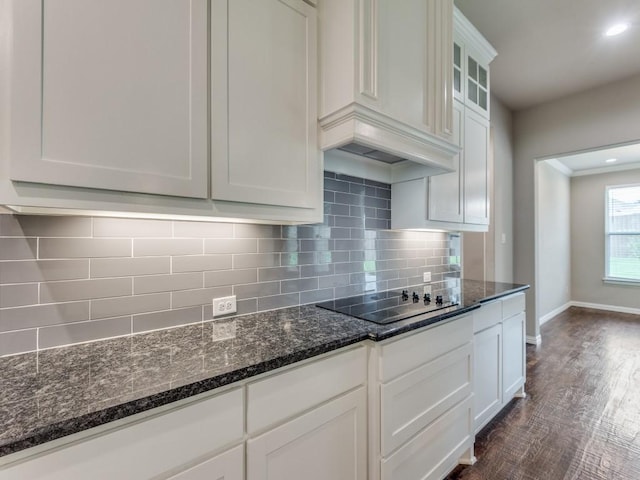 kitchen featuring tasteful backsplash, white cabinetry, dark hardwood / wood-style flooring, dark stone counters, and black electric cooktop