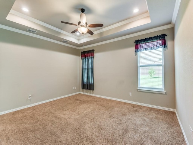 spare room with ceiling fan, ornamental molding, a raised ceiling, and light carpet