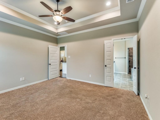 unfurnished bedroom featuring ceiling fan, ornamental molding, a tray ceiling, and light carpet