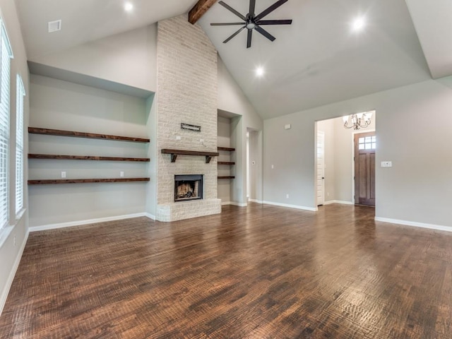 unfurnished living room featuring high vaulted ceiling, a fireplace, a healthy amount of sunlight, ceiling fan with notable chandelier, and beamed ceiling