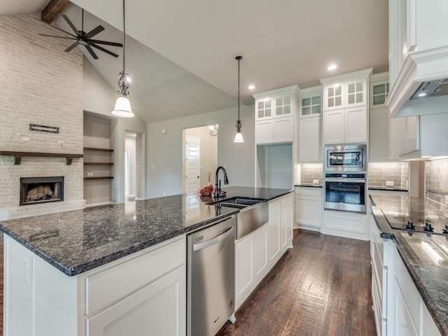 kitchen with white cabinetry, decorative light fixtures, a center island with sink, appliances with stainless steel finishes, and beam ceiling