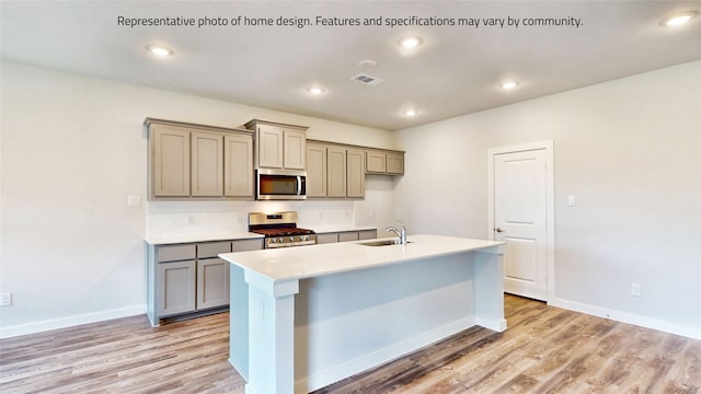 kitchen featuring a center island with sink, sink, stainless steel appliances, and light hardwood / wood-style floors