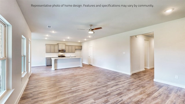 unfurnished living room with light hardwood / wood-style flooring, ceiling fan, and a wealth of natural light