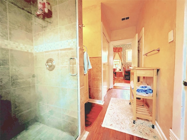 bathroom with an enclosed shower, hardwood / wood-style floors, and tile walls