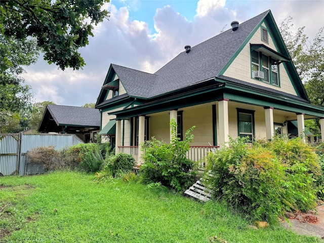 view of property exterior with a porch, cooling unit, and a lawn