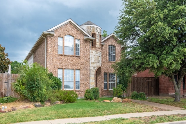 traditional-style house with stone siding, brick siding, a front yard, and fence