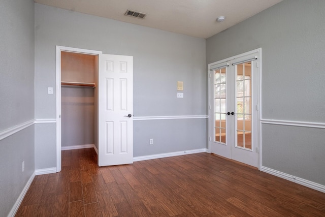 unfurnished bedroom featuring dark wood-type flooring, french doors, visible vents, and baseboards