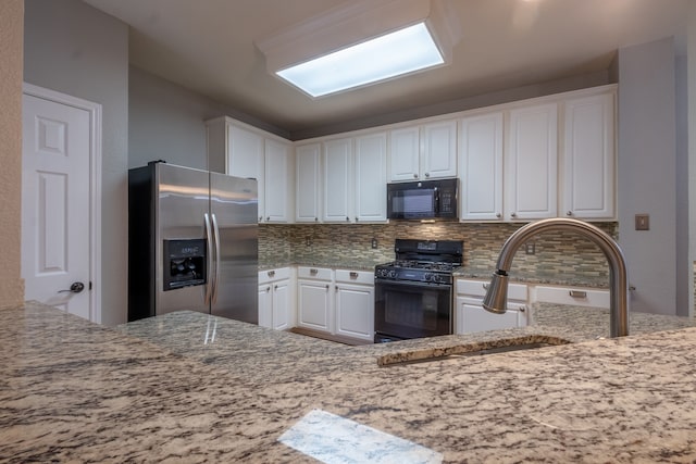 kitchen featuring white cabinetry, backsplash, black appliances, and light stone countertops