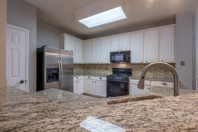 kitchen featuring light stone counters, white cabinets, decorative backsplash, and black appliances