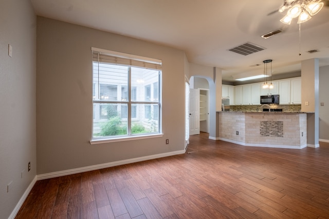 unfurnished living room featuring wood-type flooring and ceiling fan