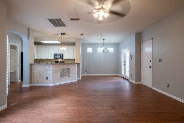 kitchen featuring ceiling fan with notable chandelier, white cabinets, stone countertops, backsplash, and dark wood-type flooring