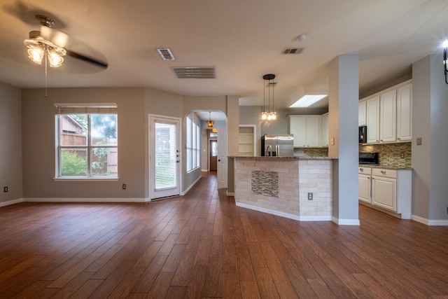 kitchen with white cabinets, stainless steel fridge with ice dispenser, light stone counters, dark hardwood / wood-style floors, and backsplash