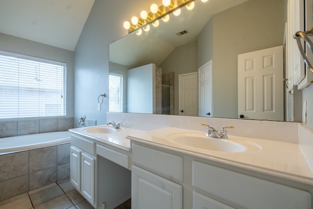 bathroom with a relaxing tiled tub, tile patterned flooring, dual bowl vanity, and vaulted ceiling