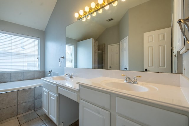 bathroom with a garden tub, vaulted ceiling, a sink, and tile patterned floors