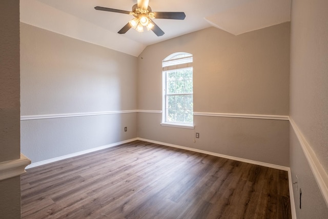 empty room featuring lofted ceiling, baseboards, dark wood finished floors, and a ceiling fan