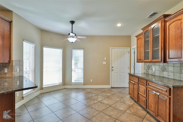 kitchen featuring light tile patterned flooring, decorative backsplash, and dark stone counters