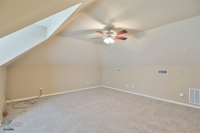 additional living space with ceiling fan, lofted ceiling with skylight, and carpet flooring