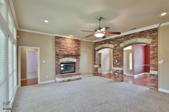 unfurnished living room featuring light carpet, ceiling fan, ornamental molding, and a fireplace