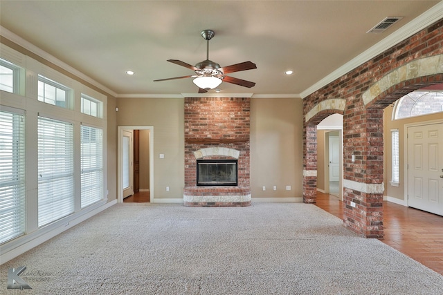 unfurnished living room featuring ceiling fan, a brick fireplace, light carpet, and ornamental molding