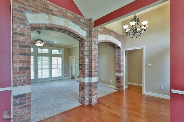 interior space with crown molding, ceiling fan with notable chandelier, hardwood / wood-style floors, and decorative columns