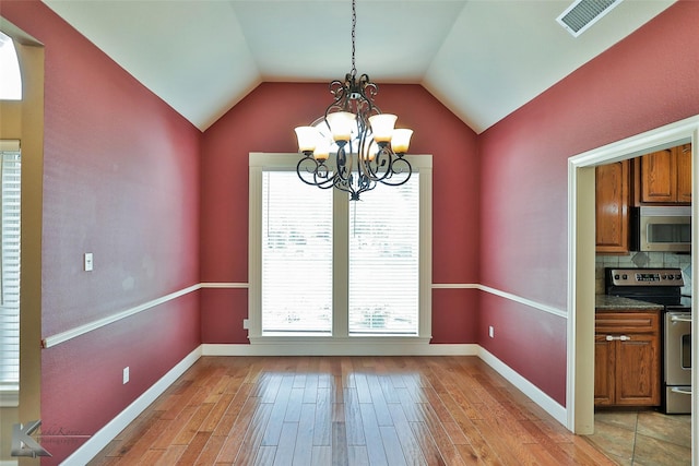 unfurnished dining area featuring light hardwood / wood-style flooring, a chandelier, and vaulted ceiling