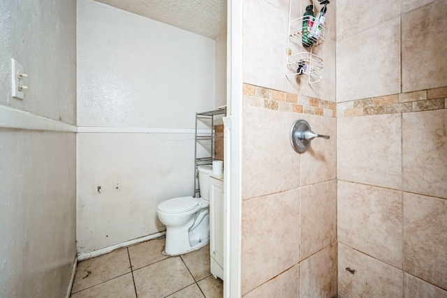 bathroom with a textured ceiling, tiled shower, and toilet