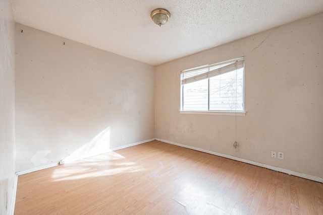 empty room with wood-type flooring and a textured ceiling