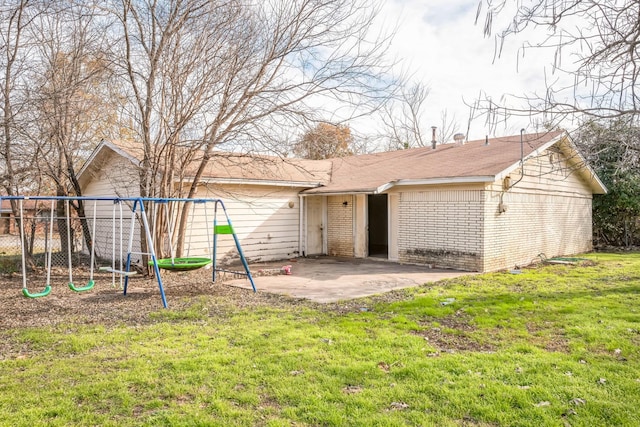 back of house featuring a lawn, a playground, and a patio area