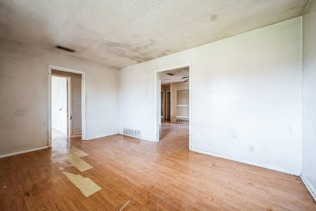 empty room with a textured ceiling and light hardwood / wood-style flooring