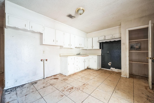 kitchen with a textured ceiling and white cabinetry