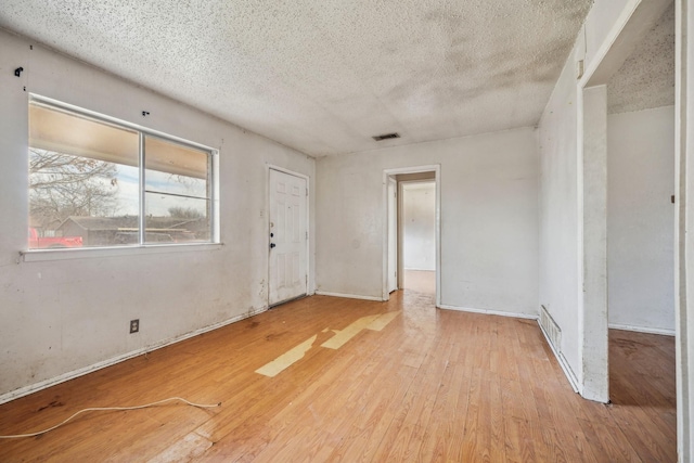 empty room with light hardwood / wood-style floors and a textured ceiling