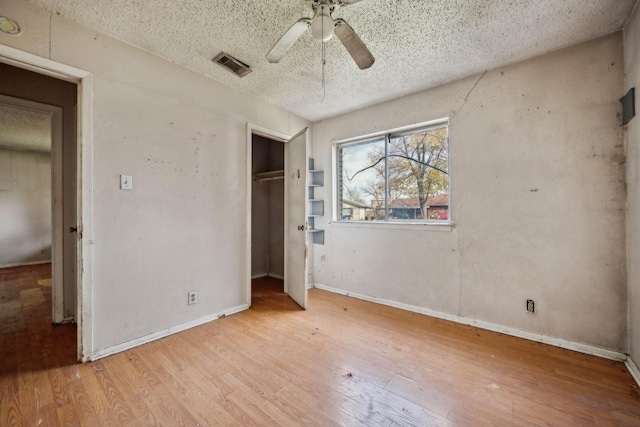 unfurnished bedroom with ceiling fan, light wood-type flooring, and a textured ceiling