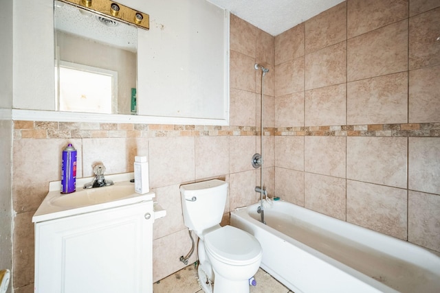 full bathroom featuring toilet, a textured ceiling, tile walls, tiled shower / bath combo, and vanity