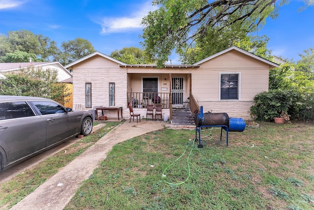 ranch-style home featuring covered porch and a front yard