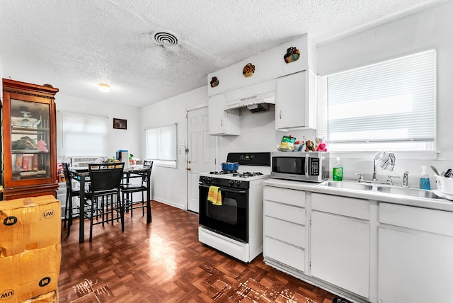 kitchen featuring white cabinetry, a wealth of natural light, white range with gas cooktop, and dark parquet floors