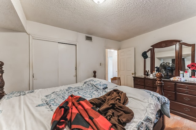 bedroom with light hardwood / wood-style flooring, a closet, and a textured ceiling