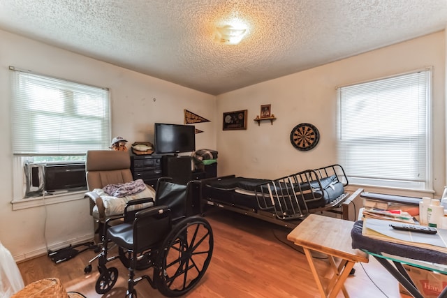 bedroom featuring wood-type flooring, cooling unit, and a textured ceiling