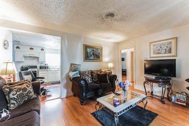 living room with a textured ceiling and light wood-type flooring