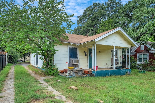 bungalow-style house with a porch, cooling unit, and a front lawn