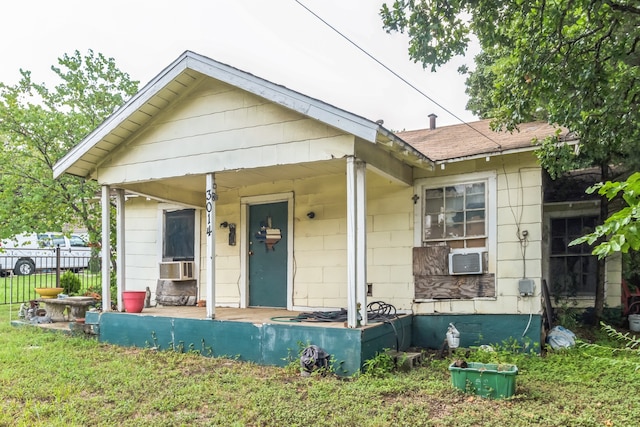 bungalow featuring covered porch, cooling unit, and a front yard