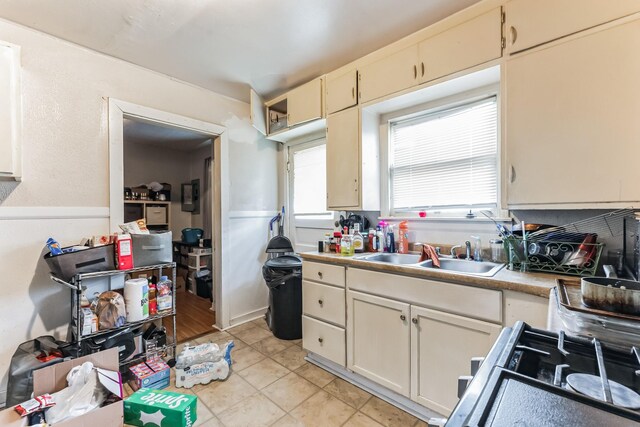 kitchen with cream cabinets, sink, range, and light tile patterned floors