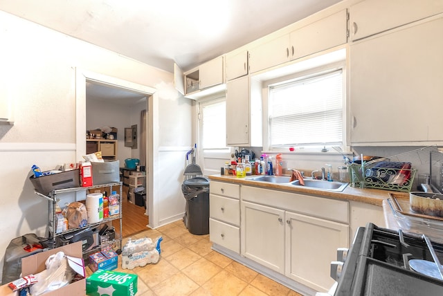 kitchen with sink, light tile patterned flooring, white cabinetry, and stove