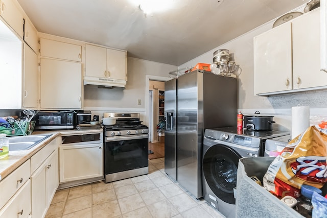 kitchen with appliances with stainless steel finishes, sink, washer / dryer, cream cabinetry, and light tile patterned flooring