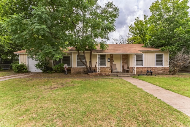 single story home featuring covered porch, a garage, and a front yard